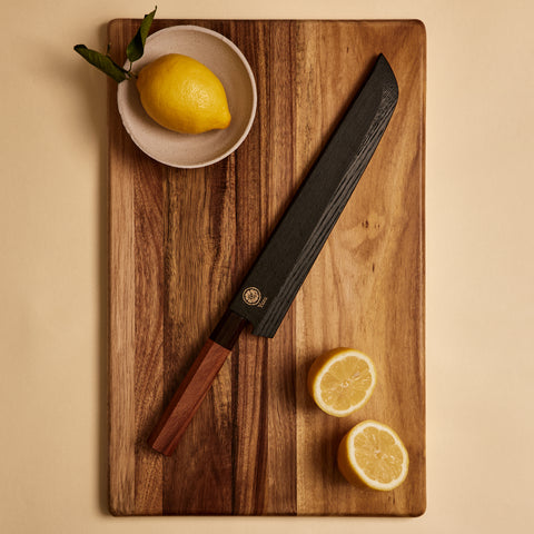 Bread knife in wooden saya knife sheath on a cutting board with lemons