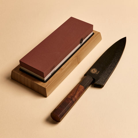 Petty knife in saya sheath next to dual-sided sharpening stone