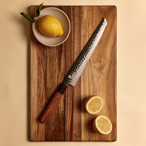 Bread knife from the four knife set on a cutting board with lemons