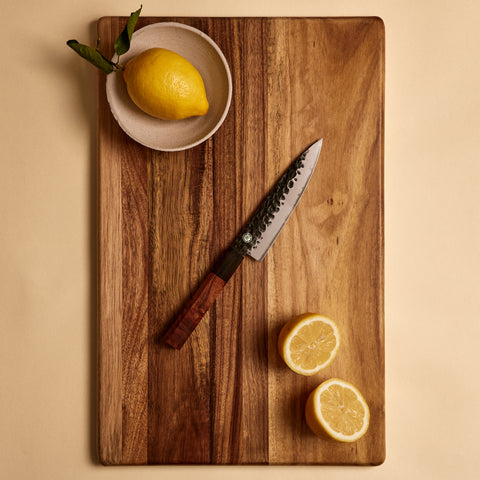 Petty knife from the four knife set on a cutting board with lemons