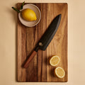 Gyuto knife in wooden saya knife sheath on a cutting board with lemons