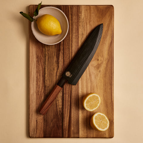 Gyuto knife in wooden saya knife sheath on a cutting board with lemons