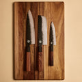Yuzu Knives Japanese steel three knife set — Nakiri, Gyuto, and Petty on a cutting board