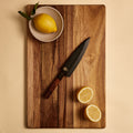 Petty knife in its wooden saya sheath on a cutting board with lemons